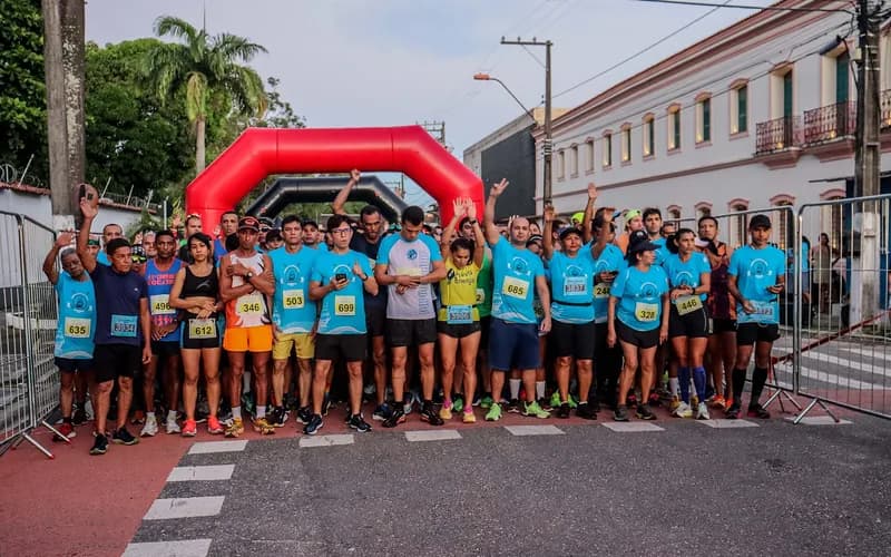 Grupo de corredores em prova de rua com público na lateral.