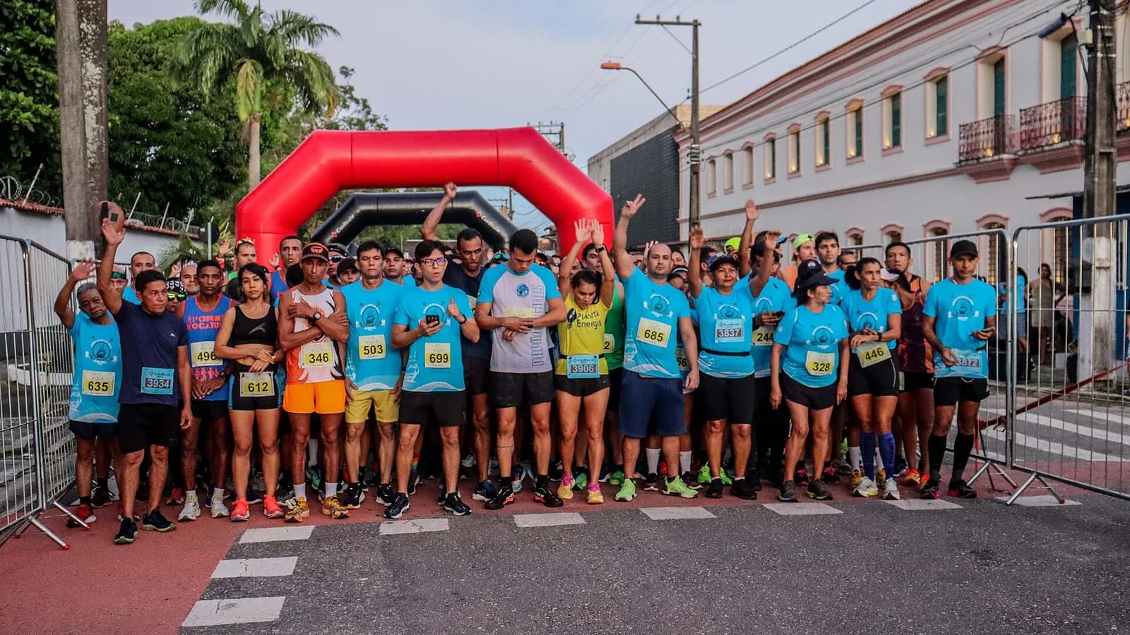 Corredores em prova de rua vistos de frente, com público ao fundo.